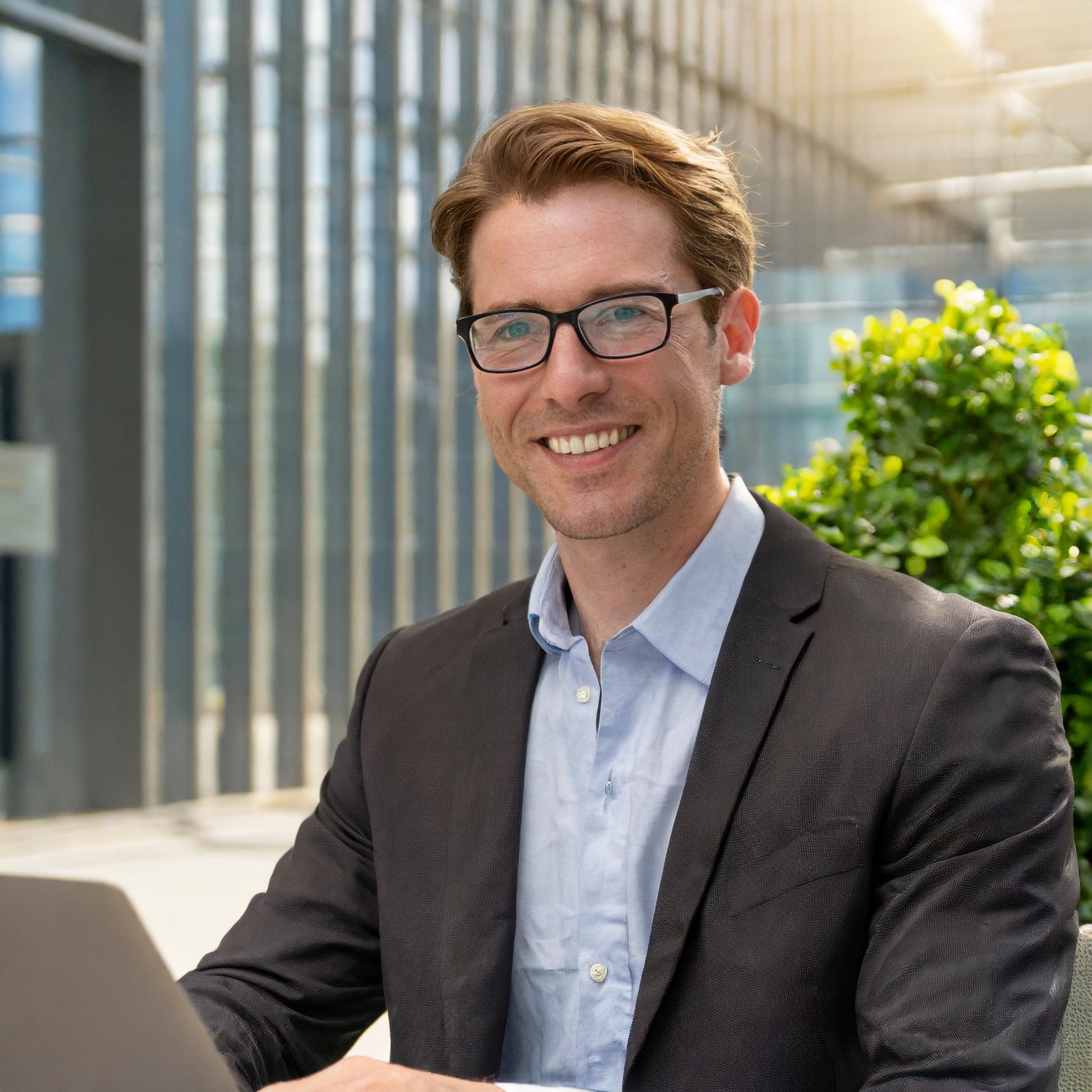 Man wearing glasses and smiling in a professional environment